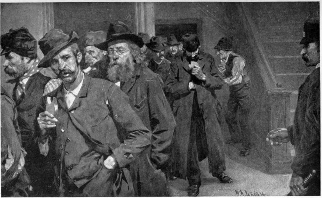A line of men in worn out clothes exiting through a door watched
by a policeman. Many of them are eating bread.